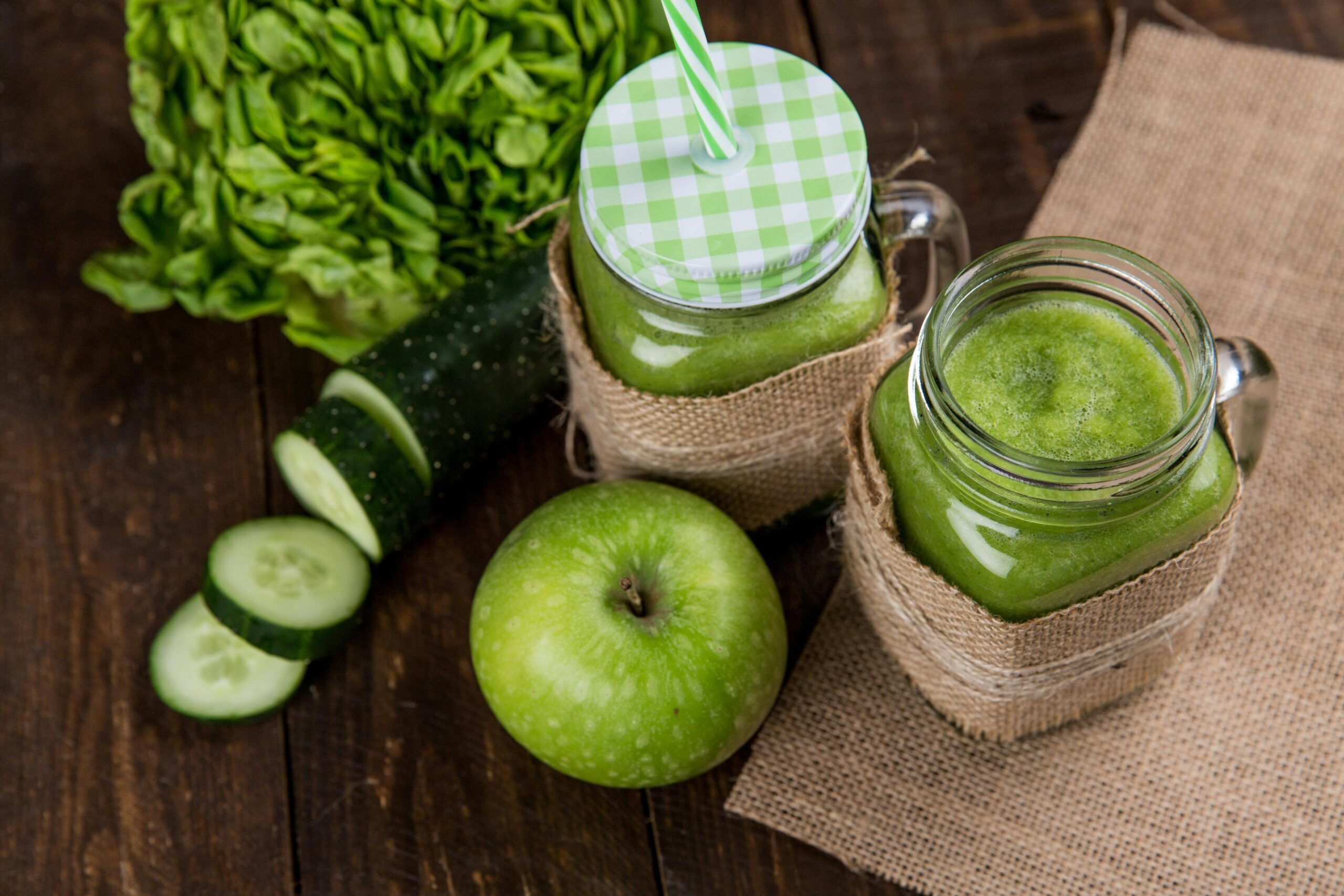 Dois copos de suco verde detox com maçã verde, pepino e folhas verdes, destacando bebidas saudáveis para desintoxicação.