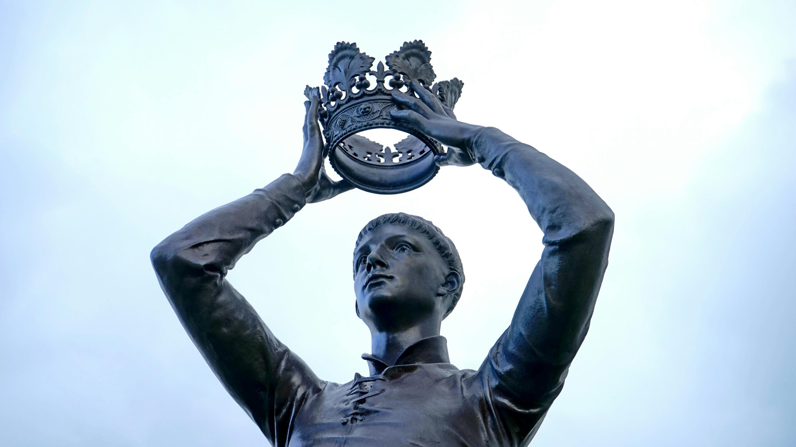 Estátua de homem atlético segurando coroa acima da cabeça simbolizando força, vitória e níveis saudáveis de testosterona masculina